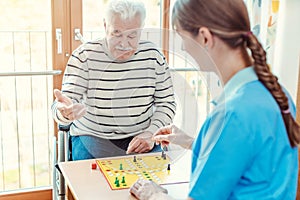 Nurse and senior in retirement home playing a board game