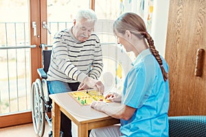 Nurse and senior in retirement home playing a board game