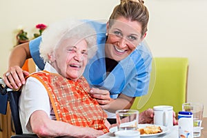 Nurse with senior woman helping with meal photo