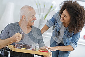 Nurse serving breakfast to senior man at home