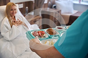 Nurse serving dietary meal to inpatient in medical facility ward