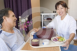 Nurse Serving A Patient A Meal In His Bed