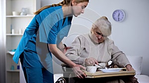 Nurse serving unappetizing diet dinner to old handicapped woman, taking care