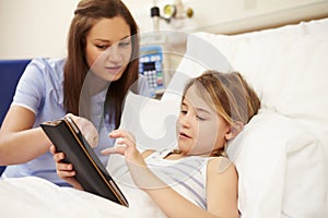 Nurse Sitting By Girl's Bed In Hospital With Digital Tablet