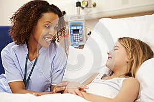 Nurse Sitting By Young Girl's Bed In Hospital