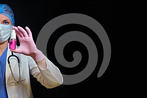 A nurse sprays a can of red sanitizer, black background. Doctor in medical gloves with disinfectant, close-up. Hand hygiene