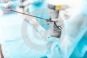 Nurse in sterile gloves holding laparoscopic instrument