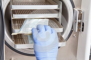 Nurse is sterilizing bandages in autoclave at dental office