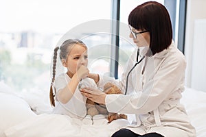 Nurse with stethoscope examining coughing little girl