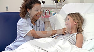 Nurse With Stethoscope Examining Young Girl In Hospital Bed