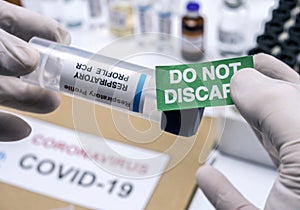 Nurse sticks label indicating not to discard from a covid-19 patient sample in a hospital