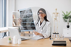 Nurse studying CT brain scans in doctor& x27;s office interior