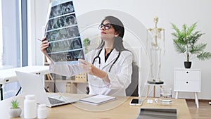 Nurse studying CT brain scans in doctor's office interior