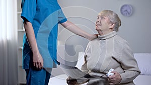 Nurse supporting crying old woman with brain roentgen, fatal diagnosis, health