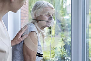 Nurse supporting sick senior woman with oxygen mask