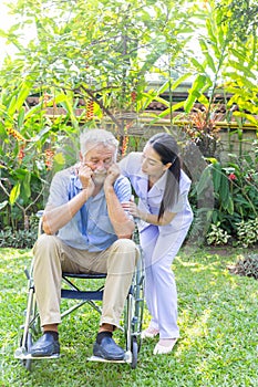 Nurse take care a depressed thoughtful senior retirement man on his wheelchair in a garden in his home