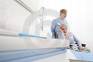 Nurse take care elderly woman isolated on wheelchair near bed in hospital room, concept of loneliness and old age diseases