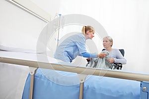 Nurse take care elderly woman isolated on wheelchair near bed in hospital room, concept of loneliness and old age diseases