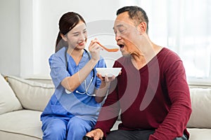 nurse takes care elderly man by having lunch in his room at home. healthcare concept