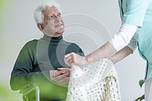 Nurse taking care of happy paralyzed elderly man in a wheelchair