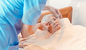 Nurse taking care of sleeping senior woman in the nursing home