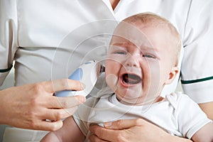 Nurse Taking Crying Baby's Temperature With Digital Thermometer