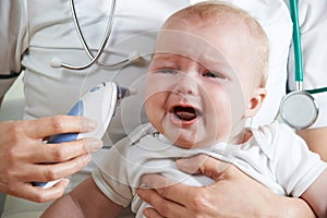 Nurse Taking Crying Baby's Temperature With Digital Thermometer