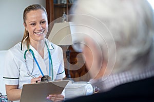 Nurse Taking Medical Notes From Senior Man At Home On Visit