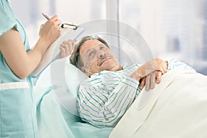 Nurse taking notes of old patient