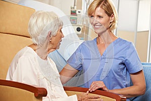 Nurse Taking To Senior Female Patient Seated In Chair