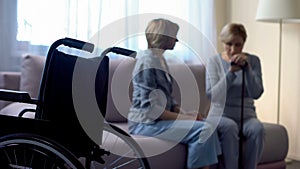 Nurse talking with depressed disabled senior woman in rehabilitation center