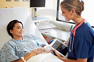 Nurse Talking To Female Patient On Ward Using Digital Tablet