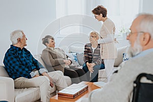 Nurse is talking to new patients sitting on the sofa in a retirement home