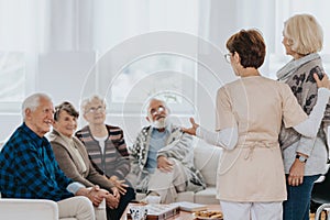 Nurse is talking to new patients sitting on the sofa in a retirement home