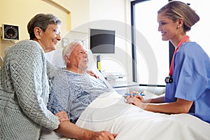 Nurse Talking To Senior Couple In Hospital Room