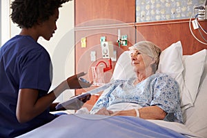 Nurse Talking To Senior Female Patient In Hospital Bed photo