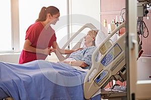 Nurse Talking To Senior Female Patient In Hospital Bed