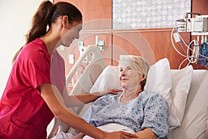 Nurse Talking To Senior Female Patient In Hospital Bed