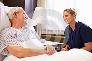 Nurse Talking To Senior Male Patient In Hospital Bed