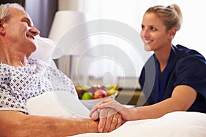 Nurse Talking To Senior Male Patient In Hospital Bed