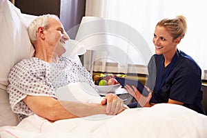 Nurse Talking To Senior Male Patient In Hospital Bed