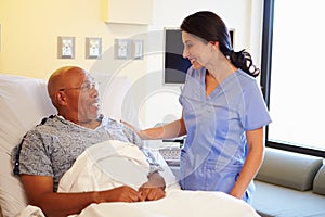 Nurse Talking To Senior Male Patient In Hospital Room