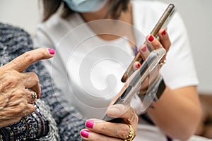 Nurse teaching elder woman how to use mobile phone, senior grandmother learning to use smartphone at nursing home