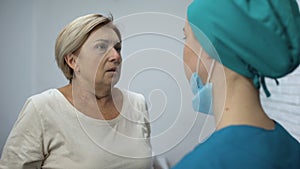 Nurse telling mature patient shocking news, terrified woman crying hysterically