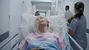 Nurse transports elderly woman down medical center hallway