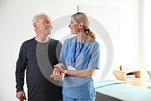 Nurse in uniform assisting elderly woman