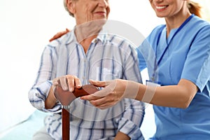 Nurse in uniform assisting elderly woman indoors