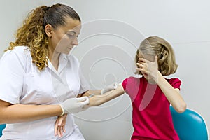 Nurse uses a syringe to vaccinate the child girl. Inoculation in the shoulder, in the hospital. Medicine, healthcare, pediatry and