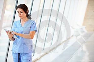 Nurse Using Digital Tablet In Corridor Of Modern Hospital