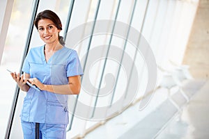 Nurse Using Digital Tablet In Corridor Of Modern Hospital